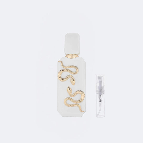 White perfume bottle with gold snake design on a light gray background