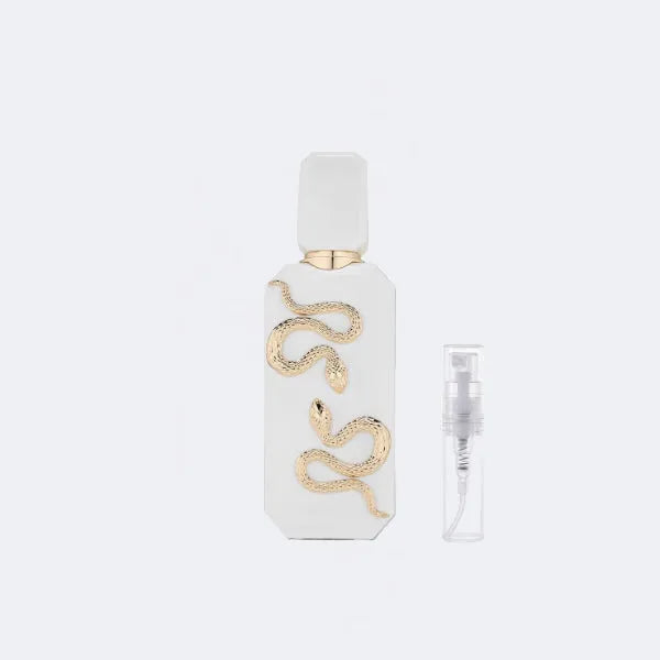 White perfume bottle with gold snake design on a light gray background