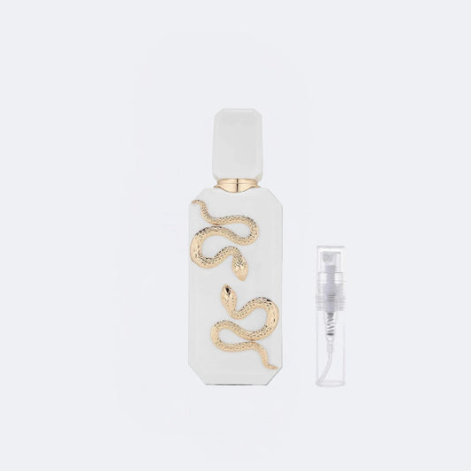 White perfume bottle with gold snake design on a light gray background